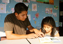 Father helping his daughter to read in a REAULA project school